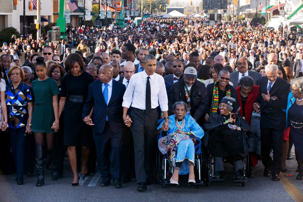 In March of 2015, President Barack Obama, center, walks as he holds hands with Amelia Boynton Robinson, who was beaten during Bloody Sunday, as they and the first family and others including Rep. John Lewis, D-Ga., left of Obama, walk across the Edmund Pettus Bridge in Selma, Ala. for the 50th anniversary of Bloody Sunday, a landmark event of the civil rights movement. From front left are Marian Robinson, Sasha Obama, First Lady Michelle Obama, President Obama, Boynton and Adelaide Sanford, also in wheelchair.
